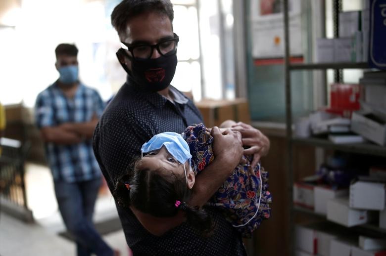 A man carries his daughter as they wait at a local health centre to conduct tests for the coronavirus disease (COVID-19), amid the spread of the disease, in New Delhi, India July 4, 2020. REUTERS/Adnan Abidi